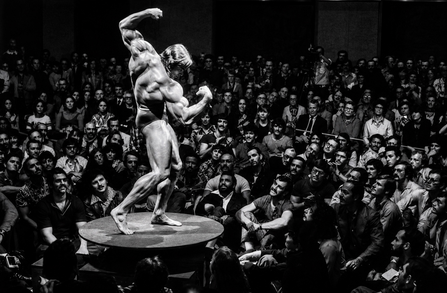 Arnold Schwarzenegger posing before a crowd, Pumping Iron era, 1977